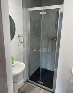 uma casa de banho com uma cabina de duche em vidro e um lavatório. em Lochaber Apartments em Fort William