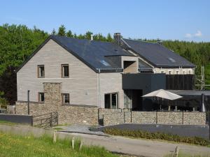 uma grande casa cinzenta com uma parede de pedra em Valgrange em Tenneville