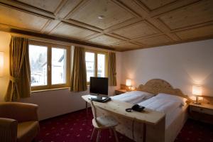 a bedroom with a bed and a desk with a computer at Hotel Seraina in Sils Maria
