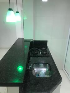 Green Flat Fortaleza في فورتاليزا: سطح مكتب أسود مع ضوء أخضر في مطبخ