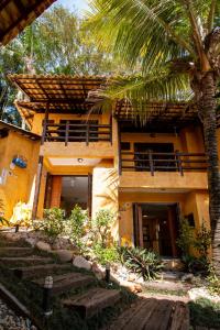 a house with a palm tree in front of it at Villa Garoupeta - Apartamentos in Bombinhas