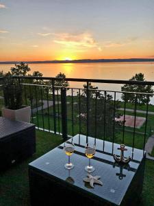 dwa kieliszki do wina na stole z widokiem na wodę w obiekcie Best Panoráma Apartman w Siófoku
