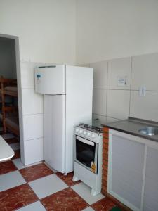 a kitchen with a stove and a refrigerator at Apartamentos Apiaí in Ilha Comprida