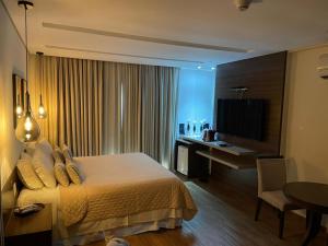 um quarto de hotel com uma cama, uma secretária e uma televisão em Hotel Mohave em Campo Grande