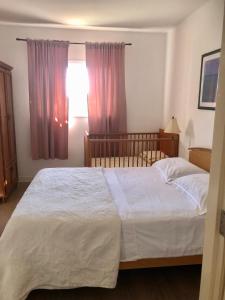 ein Schlafzimmer mit einem großen weißen Bett und einem Kinderbett in der Unterkunft Apartment Hannah in Brna