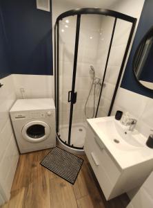 a bathroom with a shower and a sink and a washing machine at 300 metrów od plaży / 300 meters from the beach in Gdańsk