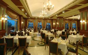 クンドゥにあるデルフィン ディーバ プルミエールの白いテーブルと椅子、シャンデリアのあるレストラン