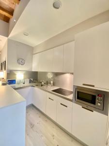 a kitchen with white cabinets and a clock on the wall at True Design in Heart of Noble BCN in Barcelona
