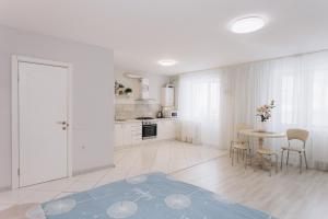 a white kitchen with a table and chairs at Apart-Hotel in Sumy