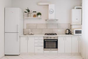 a white kitchen with white cabinets and a refrigerator at Apart-Hotel in Sumy