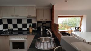 a kitchen with a sink and a stove top oven at Atico Playa Fontaiña in Vigo