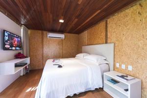 a bedroom with a white bed and a tv at BobZ Boutique Resort in Barra Grande