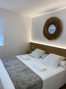 1 dormitorio con 1 cama grande y espejo en la pared en A Fonte das Hortas Residencial, en Santiago de Compostela