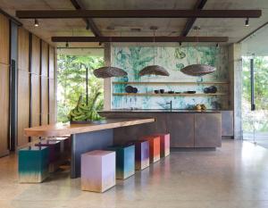 a kitchen with a wooden counter with colorful chairs at Art Villas Costa Rica in Uvita
