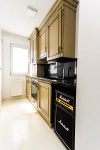 a kitchen with wooden cabinets and a black dishwasher at Apartament Amaya in Bistriţa