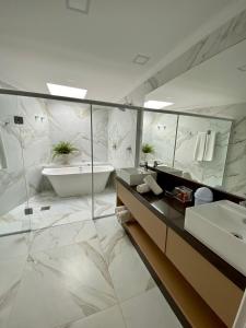 a bathroom with a sink and a tub and a mirror at Estaleiro Guest House in Balneário Camboriú +144 photos