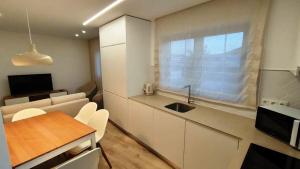 a kitchen with white cabinets and a table and a window at Green Garden Houses in Chaves
