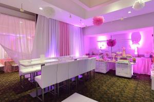 a dining room with white tables and pink curtains at Fiesta Inn Chetumal in Chetumal