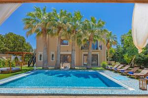 a pool with palm trees in front of a house at Prestige Residence Rhodes in Ialysos