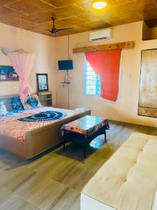 a bedroom with a bed and a table and a couch at Jungle Beach Resort in Sanyang