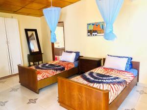 Jungle Beach Resort في Sanyang: سريرين في غرفة مع ستائر زرقاء