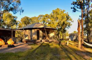 a small cabin with a hammock in a yard at Ketchup's Bank Glamping in Boonah