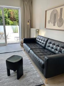 a living room with a black leather couch and a stool at Unique luxury apartment with cosy garden! in Ghent