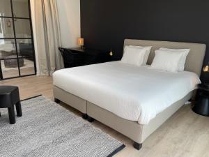 1 dormitorio con 1 cama grande con sábanas blancas y almohadas en Unique luxury apartment with cosy garden! en Gante