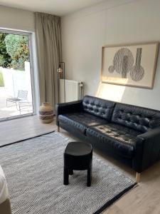 a living room with a black leather couch and a stool at Unique luxury apartment with cosy garden! in Ghent