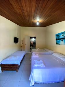 a bedroom with two beds and a tv in it at FLATS VASCONCELOS in Itacaré