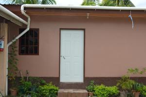 una porta bianca sul lato di una casa con piante di Apartamentos y Hostal RUDON #1 a Puerto Cortés