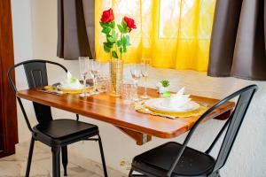une table en bois avec deux chaises et un vase avec des roses dans l'établissement Le Jardin Secret Guyanais avec Piscine et Jardin de 70 m2, à Cayenne