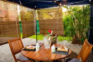 a wooden table with food and flowers on it at Le Jardin Secret Guyanais avec Piscine et Jardin de 70 m2 in Cayenne +7 photos