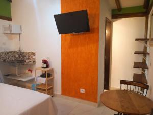 a room with a bed and a tv on a wall at Chalé de Charme Mandomai in Ilhabela