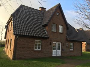 a brown brick house with a black roof at Heimathafen - a09672 in Wrixum