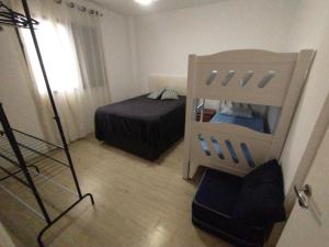 ein Zimmer mit einem Schlafzimmer mit einem Bett und einem Stuhl in der Unterkunft O Canto do Forte - Praia Grande in Praia Grande
