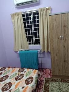 a bedroom with a bed and a window with curtains at Aliza Scawa Homestay in Kuala Pilah