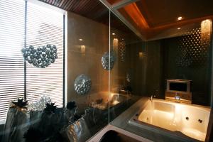 uma casa de banho com uma banheira, uma televisão e uma janela em The Yorker Deluxe Motel em Taoyuan
