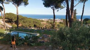 a woman standing next to a pool with a view of the ocean at Villa Maresme & Villa Rosa in Mataró