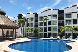 a resort with a swimming pool and a building at Hermoso departamento con alberca in Manzanillo