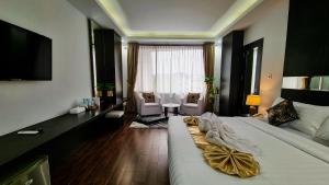 a bedroom with a large bed and a living room at Hotel Rasamala in Geutieue