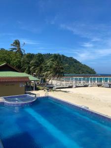 - une piscine à côté d'une plage avec un pont dans l'établissement Tioman Santai Resort, à l'Île Tioman