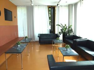 ein Wohnzimmer mit Sofas und Tischen in der Unterkunft Jugendherberge Stuttgart Neckarpark in Stuttgart