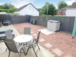 a patio with a table and chairs and a fence at Cheerful One bedroom cottage with parking space. in Glasgow