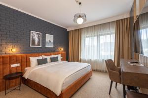 ein Hotelzimmer mit einem großen Bett und einem Schreibtisch in der Unterkunft UpperHouse Suites & More in Braşov