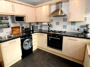 a kitchen with a stove and a dishwasher at Cheerful One bedroom cottage with parking space. in Glasgow