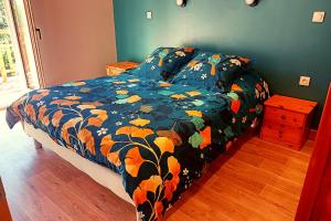 ein Bett mit einer blauen Bettdecke mit Blättern darauf in der Unterkunft Le Balcon du grand bec in Planay