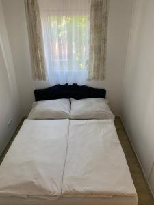 łóżko w małym pokoju z oknem w obiekcie Mineral apartman Crystal w mieście Sóstófürdő +1 zdjęcie
