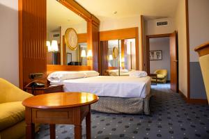 um quarto de hotel com duas camas e uma mesa em Hotel los Bracos em Logroño