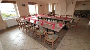 uma sala de jantar com uma mesa longa com guardanapos vermelhos em Blatenský dvůr em Pardubice
